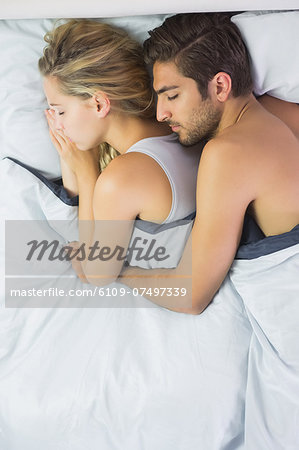Relaxed couple sleeping and spooning in bed in the bedroom