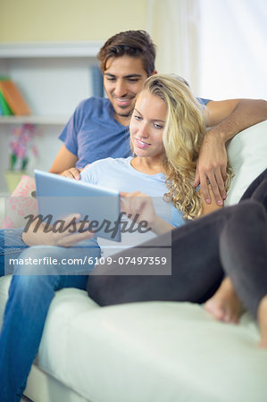 Attractive calm couple using a tablet sitting in the living room