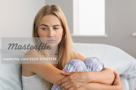 Lonely blonde sitting on the floor at home in bedroom