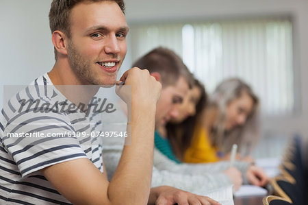 Happy handsome student looking at camera in classroom in a college