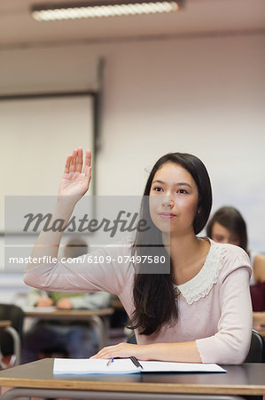 Focused asian student raising her hand in class at the university