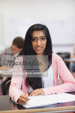 Smiling indian student listening in class looking at camera at the university