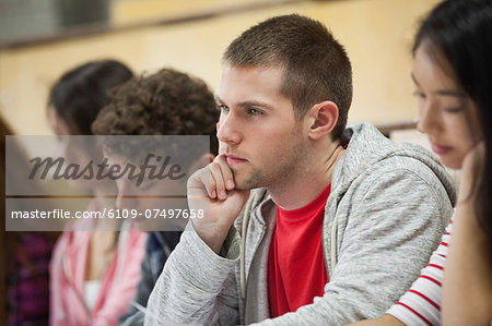 Row of concentrating students taking notes in a lecture hall in college