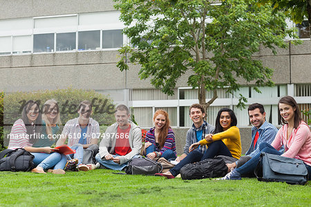 Group of students smiling at camera on the grass on campus at the university