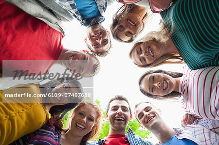 Group of students smiling down at camera in a circle on campus at the university