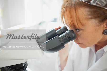 Close up of female scientist looking through a microscope  in a laboratory