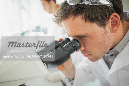 Young male scientist looking through a microscope in a laboratory