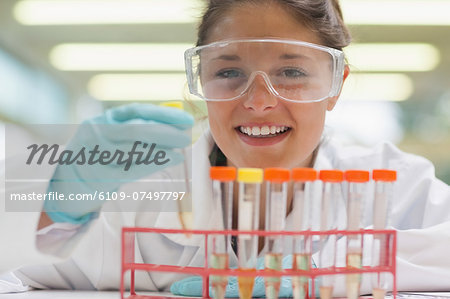 Cheerful student placing test tube in rack in lab at college