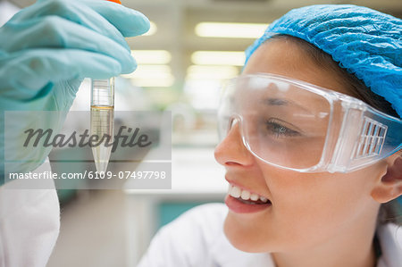 Smiling student looking closely at test tube in lab at college