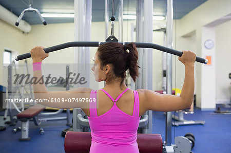 Toned woman exercising on weight machine in weights room of gym