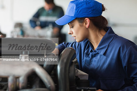 Focused trainee checking machine in workshop