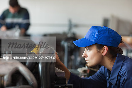 Calm trainee checking machine in workshop Calm trainee checking machine in workshop