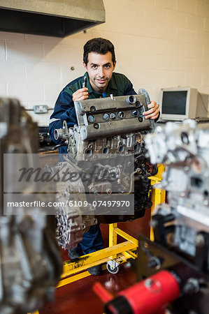 Content repairman standing behind an engine in workshop