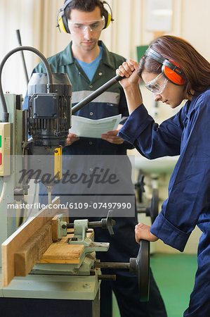 Focused trainee using drill in workshop