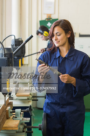 Happy trainee holding tool in workshop