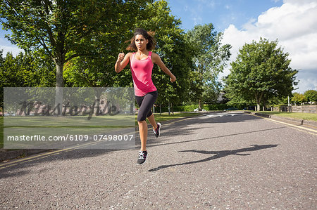 Full length of a healthy young woman jogging on pathway in the park
