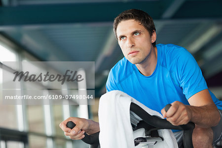 Determined young man working out at spinning class in gym