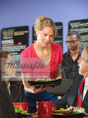 Apologetic server bringing salad to upset business man