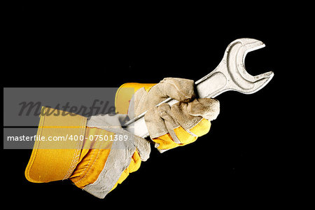 leather work gloves holding a  wrench over black