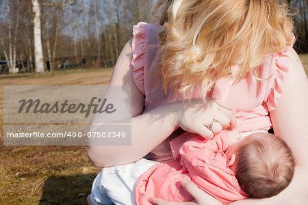 Mother is feeding her baby on the field