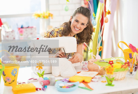 Happy young woman making easter pot holder mitts in studio