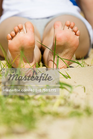 children's feet on a sandy beach in summer