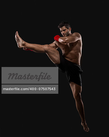 Portrait of a muscular man practicing body combat against a dark background