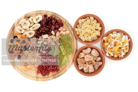 Dried fruit selection on a wooden board and in terracotta bowls over white background.