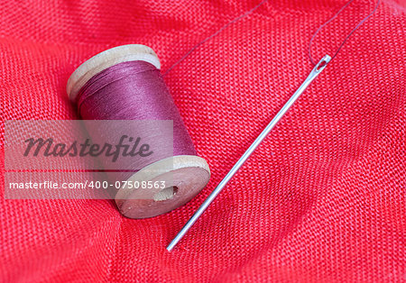 skein of thread and needle on the red cloth