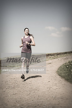 Photo of a beautiful young woman running down a gravel road.
