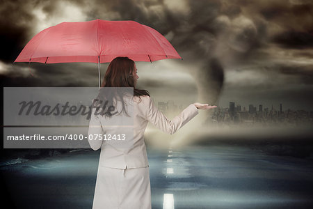 Businesswoman holding umbrella against stormy sky with tornado over road