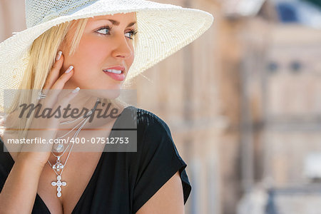 Beautiful blonde girl young woman wearing white sun hat, silver jewelry crucifix necklace and little black dress