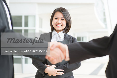 Business deal, Asian businessmen handshaking. Focus on assistant or secretary. Modern  office building architecture background.