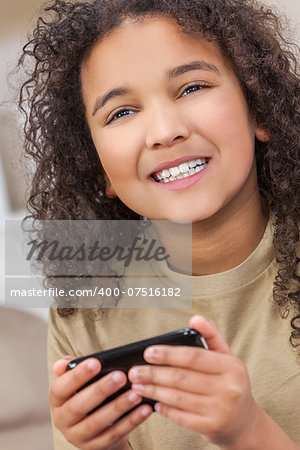 Beautiful young mixed race interracial African American girl child smiling with perfect white teeth using smart cell phone for texting or playing video games