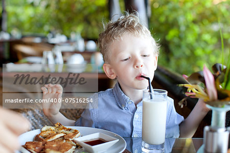 cute little boy drinking his milk at the breakfast, delicious breakfast at the resort