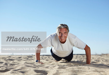 Senior man doing push ups on beach