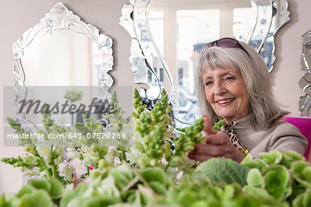 Senior woman looking at flowers in florist shop