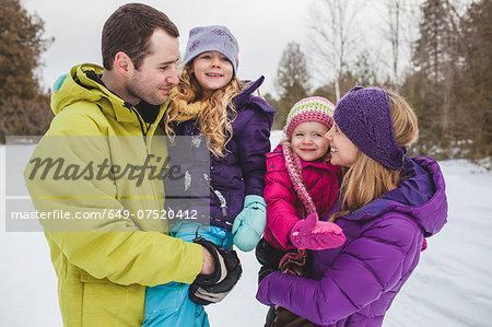 Mother and father carrying daughters in snow