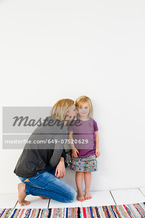 Studio shot of mother kneeling next to young daughter