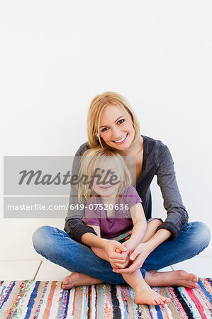 Studio portrait of mother and young daughter on rug