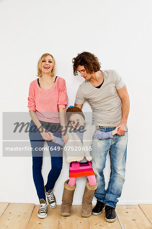 Studio shot of couple with young daughter wearing big boots