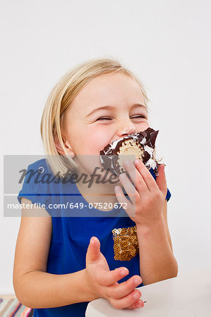 Studio portrait of young girl eating chocolate marshmallow