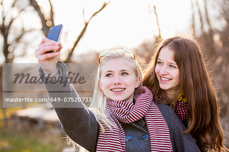 Teenage girls photographing themselves with smartphone