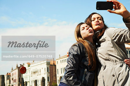 Mother and daughter taking selfie on smartphone, Venice, Italy