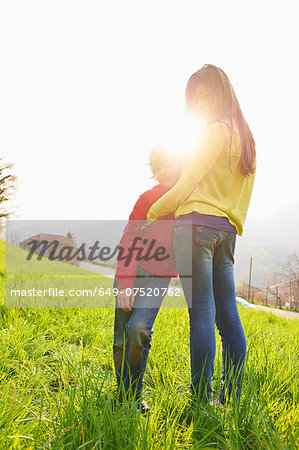 Young boy and older sister in grassy field