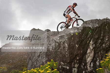 Young man mountain biking on top of rock formation
