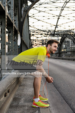 Young male runner resting on bridge