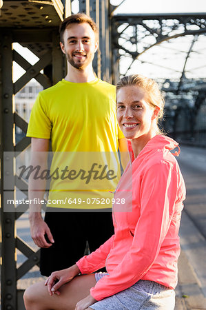 Portrait of young male and female runners on bridge