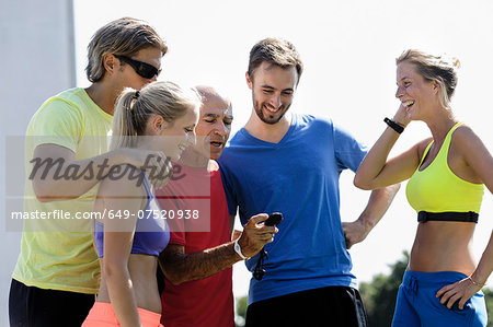 Mature male trainer and a group of adult runners checking stopwatch