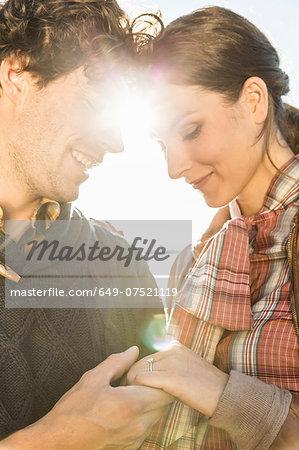 Man holding woman's hand, woman wearing engagement ring